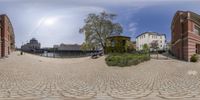 fisheye lens view of buildings, a park and a clock tower by the water