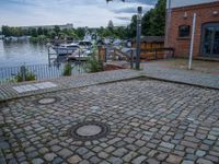 a paved area with two small water outlets on the brick pavement and several small boats in the water