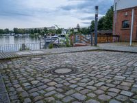 a paved patio sitting on top of a sidewalk next to a river bank in a city