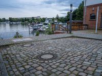 a paved patio sitting on top of a sidewalk next to a river bank in a city