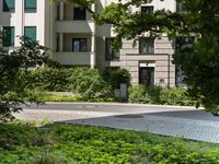 a man riding a skateboard down the street next to bushes and trees with apartment buildings