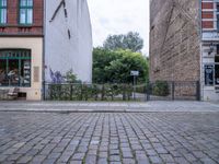 the black fire hydrant is beside a large bricked area with metal fence in front