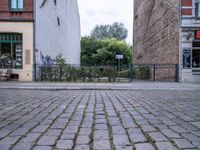 the black fire hydrant is beside a large bricked area with metal fence in front