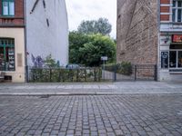 the black fire hydrant is beside a large bricked area with metal fence in front