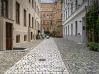 people are walking in an alley of a city with lots of cobblestones on the sidewalk