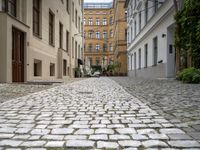 people are walking in an alley of a city with lots of cobblestones on the sidewalk