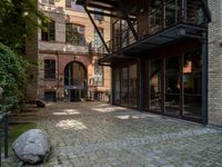 a stone with two big stones in it sitting in a courtyard space near a building