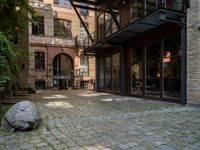 a stone with two big stones in it sitting in a courtyard space near a building