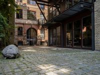 a stone with two big stones in it sitting in a courtyard space near a building