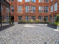 an empty parking lot with plants in the ground and on the side of the building, there is an enclosed area and windows