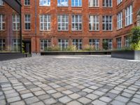 an empty parking lot with plants in the ground and on the side of the building, there is an enclosed area and windows