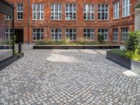 an empty parking lot with plants in the ground and on the side of the building, there is an enclosed area and windows