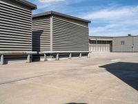 an empty parking lot near some large storage units and a building with corrugated siding and metal beams