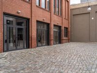 the sidewalk is paved with cobblestones that have black steel doors and windows,