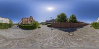 a street is shown with several trees and a large building in the background as if from fish eye view