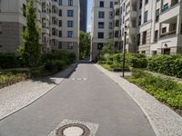 a cobblestone street with an outdoor seating area and parking spaces between two tall white apartment buildings