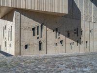 cobblestone driveway surrounded by modern buildings on sunny day with sun reflecting onto the windows