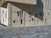 cobblestone driveway surrounded by modern buildings on sunny day with sun reflecting onto the windows