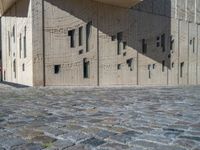 cobblestone driveway surrounded by modern buildings on sunny day with sun reflecting onto the windows