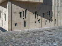 cobblestone driveway surrounded by modern buildings on sunny day with sun reflecting onto the windows