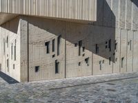 cobblestone driveway surrounded by modern buildings on sunny day with sun reflecting onto the windows