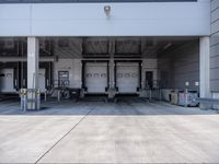 two large commercial utility trucks in a commercial building, outside a garage door and parking area