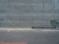 a person on a skateboard in front of a concrete wall with spray paint written on it