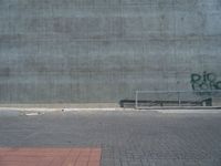 a person on a skateboard in front of a concrete wall with spray paint written on it