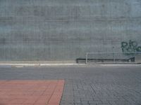 a person on a skateboard in front of a concrete wall with spray paint written on it