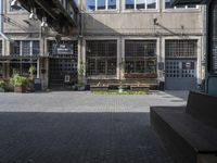 a bench sitting between two buildings in a courtyard area area with glass and brick walls