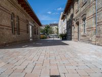 a street in an old, deserted european city has bricks and concrete flooring on each side