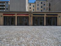 the sidewalk is paved with stones and has a bench in front of it, with no people inside