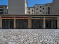 the sidewalk is paved with stones and has a bench in front of it, with no people inside