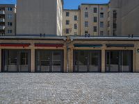 the sidewalk is paved with stones and has a bench in front of it, with no people inside