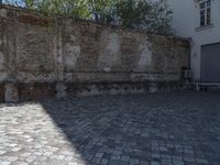 a bench sitting between two buildings in the middle of a courtyard with brick floors and walls