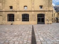 a brick plaza and the entrance to a building with windows on the side of it