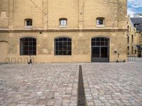 a brick plaza and the entrance to a building with windows on the side of it