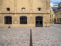 a brick plaza and the entrance to a building with windows on the side of it