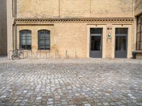 a bicycle parked in front of a tall brick building in an empty courtyard area,