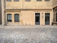 a bicycle parked in front of a tall brick building in an empty courtyard area,