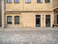 a bicycle parked in front of a tall brick building in an empty courtyard area,