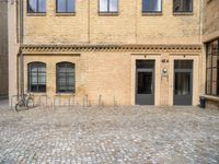 a bicycle parked in front of a tall brick building in an empty courtyard area,