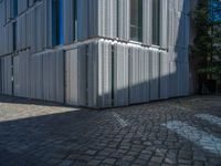 cobblestone driveway surrounded by modern buildings on sunny day with sun reflecting onto the windows