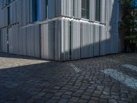 cobblestone driveway surrounded by modern buildings on sunny day with sun reflecting onto the windows