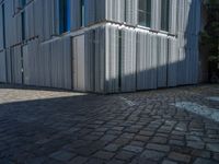 cobblestone driveway surrounded by modern buildings on sunny day with sun reflecting onto the windows