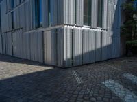 cobblestone driveway surrounded by modern buildings on sunny day with sun reflecting onto the windows