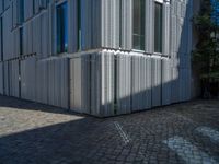 cobblestone driveway surrounded by modern buildings on sunny day with sun reflecting onto the windows