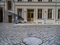 an empty parking lot with plants in the ground and on the side of the building, there is an enclosed area and windows