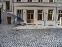 an empty parking lot with plants in the ground and on the side of the building, there is an enclosed area and windows