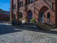 cobblestone driveway surrounded by modern buildings on sunny day with sun reflecting onto the windows